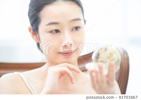 一個女人在鏡子裡檢查她的皮膚 93703867