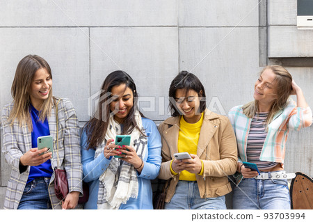 Multiracial group of teenagers have fun playing happily with smartphones. Use by millennials of cell Multiracial group of teenagers have fun playing happily with smartphones. Use by millennials of cell 93703994