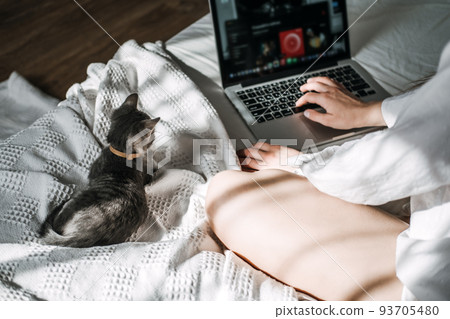 Cat and notebook. Little kitten looking the laptop while its female owner working with him at home. Cat and notebook. Little kitten looking the laptop while its female owner working with him at home. 93705480