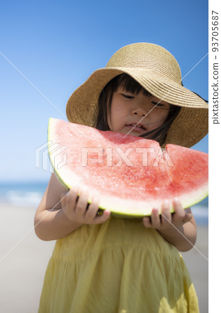 一個5歲的女孩夏天在海邊的沙灘上吃西瓜 93705687