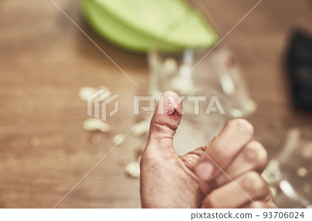 Selective focus on a cut female finger on the background of a split cup and a brush with a dustpan for cleaning. A wound with blood received when cleaning broken dishes. High quality photo 93706024