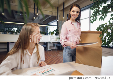 Young businesswoman holding box of personal belongings about to leave office after quitting job 93706193