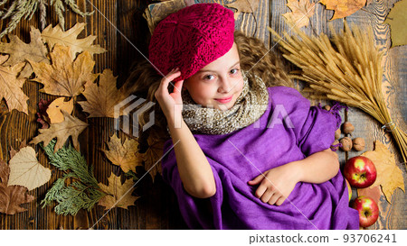 Fashion kid girl wear knitted hat beret and scarf. Autumn fashion accessories concept. Fashion trend fall season. Child lay wooden background fallen leaves top view. Knitted accessory fashion detail 93706241