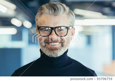 Close-up photo portrait of successful and happy senior gray-haired businessman, male investor with glasses and beard looking at camera and smiling, boss working in modern office Close-up photo portrait of successful and happy senior gray-haired businessman, male investor with glasses and beard looking at camera and smiling, boss working in modern office 93706759