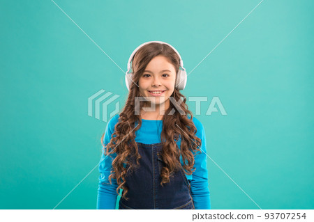 Let the music take you away. Cute little child listening to music playing in stereo headphones. Adorable girl enjoying music on blue background. Music education for small children 93707254