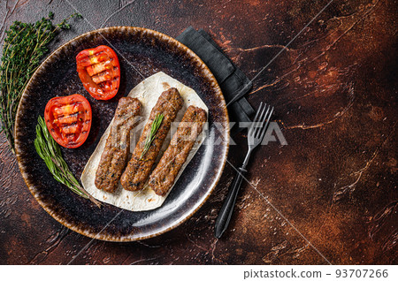 Grilled Urfa shish kebab on a plate with tomato. Dark background. top view. Copy space Grilled Urfa shish kebab on a plate with tomato. Dark background. top view. Copy space 93707266