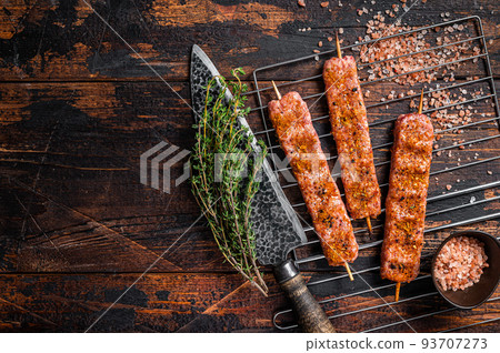Uncooked Raw Urfa shish kebab on a grill with pink salt. Wooden background. top view. Copy space Uncooked Raw Urfa shish kebab on a grill with pink salt. Wooden background. top view. Copy space 93707273