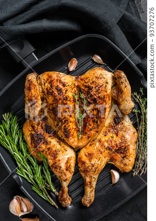 BBQ spatchcocked barbecue whole chicken on grill pan. Black background. Top view BBQ spatchcocked barbecue whole chicken on grill pan. Black background. Top view 93707276