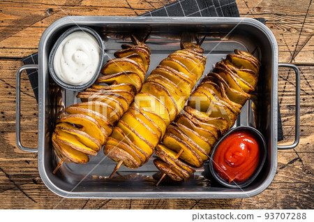 Skewered fried tornado or twist potatoes with ketchup sauce. Wooden background. Top view Skewered fried tornado or twist potatoes with ketchup sauce. Wooden background. Top view 93707288