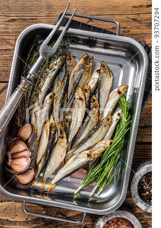 Cold Smoked sprat fishes in a kitchen tray with spices. Wooden background. Top view Cold Smoked sprat fishes in a kitchen tray with spices. Wooden background. Top view 93707294