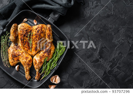 BBQ spatchcocked barbecue whole chicken on grill pan. Black background. Top view. Copy space BBQ spatchcocked barbecue whole chicken on grill pan. Black background. Top view. Copy space 93707296