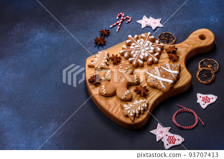 Elements of Christmas decorations, sweets and gingerbread on a wooden cutting board Elements of Christmas decorations, sweets and gingerbread on a wooden cutting board 93707413