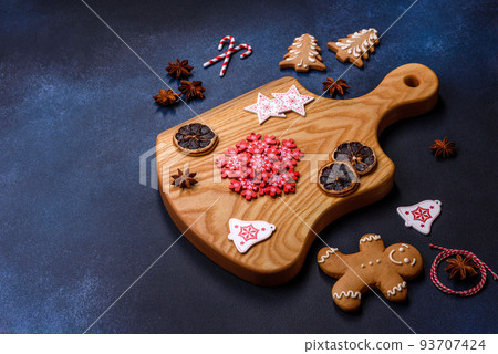 Elements of Christmas decorations, sweets and gingerbread on a wooden cutting board 93707424