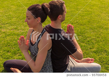 Close up of healthy man and woman doing yoga in the sunny summer park. Fitness and healthy lifestyle 93708458