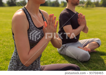 Close up of healthy man and woman doing yoga in the sunny summer park. Fitness and healthy lifestyle 93708465
