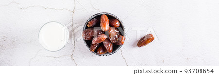 Food for the holy month of Ramadan. Dates in a bowl and milk on the table. Top view. Web banner 93708654