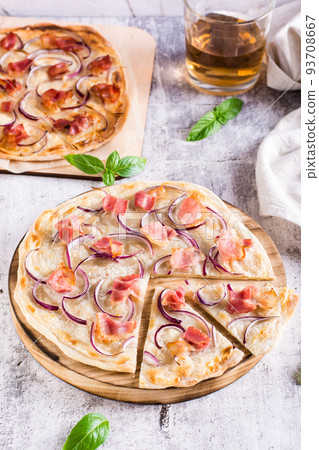 Traditional french flambee tart with cream cheese, bacon and onion on a board. Vertical view Traditional french flambee tart with cream cheese, bacon and onion on a board. Vertical view 93708667