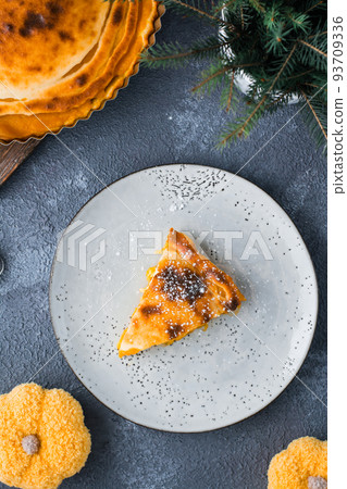 An appetizing piece of fresh sweet layered pumpkin pie in powdered sugar on a plate on the table. Thanksgiving treat. Top and vertical view 93709336
