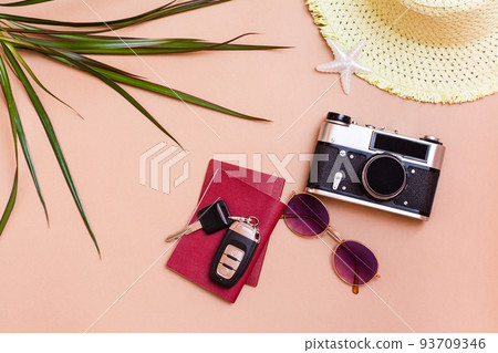 Summer bright travel flat lay with sunglasses, passports, car keys, vintage camera and straw hat on a beige background. Car travel. Top view Summer bright travel flat lay with sunglasses, passports, car keys, vintage camera and straw hat on a beige background. Car travel. Top view 93709346