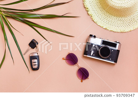 Summer bright travel flat lay with sunglasses, car keys, vintage camera and straw hat on beige background. Car travel. Top view Summer bright travel flat lay with sunglasses, car keys, vintage camera and straw hat on beige background. Car travel. Top view 93709347