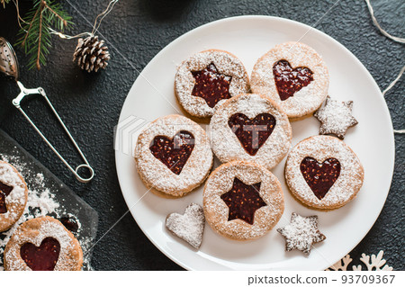 Ready Linzer cookies with berry jam on a plate on a dark background. Cooking Christmas treats. Lifestyle. Top view. Close-up 93709367