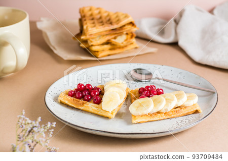 Heart shaped Belgian waffles with red berries and banana on a plate on the table. Valentine's Day. Close-up 93709484