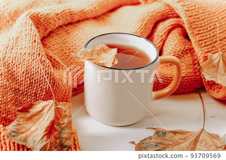 Autumn composition. Orange knitted sweater with a cup of tea and autumn leaves 93709569