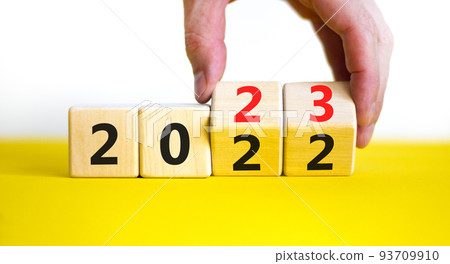 2023 happy new year symbol. Businessman turns cubes, symbolize the change from 2022 to the new year 2023. Beautiful yellow background. Copy space. Business and 2023 happy new year concept. 2023 happy new year symbol. Businessman turns cubes, symbolize the change from 2022 to the new year 2023. Beautiful yellow background. Copy space. Business and 2023 happy new year concept. 93709910