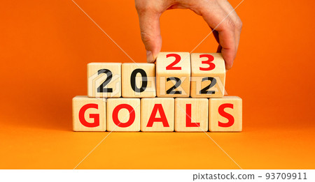 Planning 2023 goals new year symbol. Businessman turns a wooden cube and changes words Goals 2022 to Goals 2023. Beautiful orange background, copy space. Business 2023 goals new year concept. Planning 2023 goals new year symbol. Businessman turns a wooden cube and changes words Goals 2022 to Goals 2023. Beautiful orange background, copy space. Business 2023 goals new year concept. 93709911