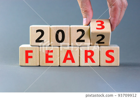 2023 fears new year symbol. Businessman turns a wooden cube and changes words Fears 2022 to Fears 2023. Beautiful grey table grey background, copy space. Business 2023 fears new year concept. 93709912