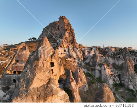 Aerial view of natural rock formations in the sunset, valley with cave houses in Cappadocia, Turkey. Natural landscape city lights at the night. Aerial view of natural rock formations in the sunset, valley with cave houses in Cappadocia, Turkey. Natural landscape city lights at the night. 93711198
