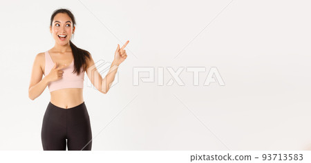 Sport, wellbeing and active lifestyle concept. Excited slim and cute asian fitness girl, female athlete pointing fingers upper right corner, showing workout equipment sale promo or gym offer Sport, wellbeing and active lifestyle concept. Excited slim and cute asian fitness girl, female athlete pointing fingers upper right corner, showing workout equipment sale promo or gym offer 93713583