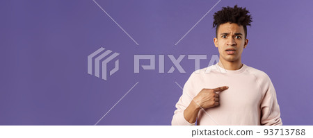 Close-up portrait of embarrassed and worried young man being named or called to principal office, pointing at himself and asking why with disbelief and anxiety, standing purple background 93713788