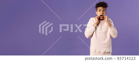 Portrait of scared hispanic guy screaming from fright, hold hands near face, open mouth gasping express fear and terrified emotion from watching horror movie, terrible accident, purple background 93714122