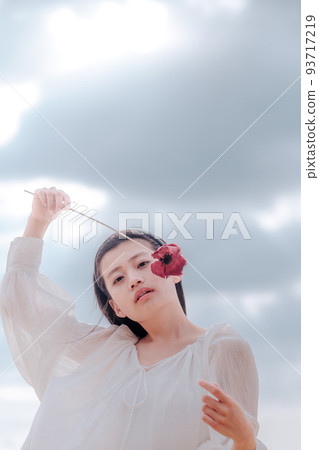 A woman in a white dress with a single flower A woman in a white dress with a single flower 93717219