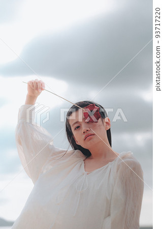 一個穿著白色連衣裙的女人,上面有一朵花 一個穿著白色連衣裙的女人,上面有一朵花 93717220