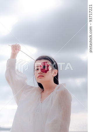 A woman in a white dress with a single flower A woman in a white dress with a single flower 93717221