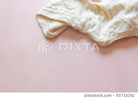 Top view of a white knitted sweater on a pink background. Top view of a white knitted sweater on a pink background. 93718192