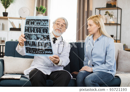 Senior male doctor explaining results of x-ray MRI image to his middle aged female patient 93721193