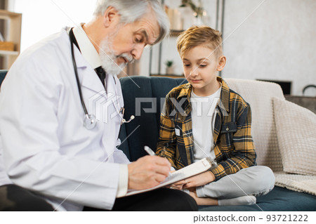 Caring mature man doctor, consulting cute sick boy, making notes in clipboard Caring mature man doctor, consulting cute sick boy, making notes in clipboard 93721222