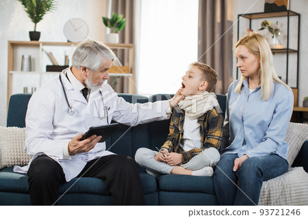 Experienced pleasant mature man doctor, examines throat of his sick preschool male patient Experienced pleasant mature man doctor, examines throat of his sick preschool male patient 93721246