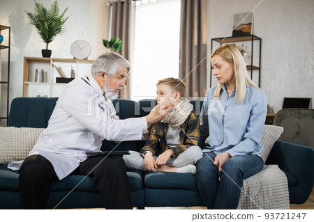 Mature doctor groping checking pain and swelling in the neck sore throatof sick male patient boy 93721247