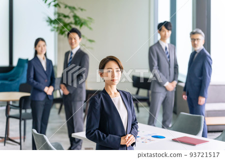 A female leader standing in an office and a group of supporting business people 93721517