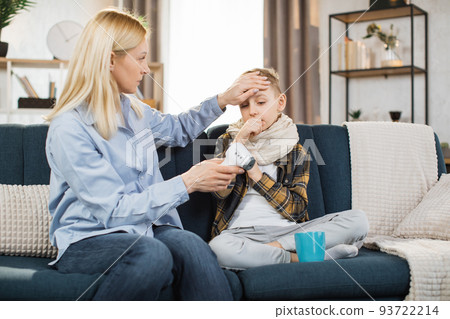 Mother measuring temperature of her teen boy using infrared thermometer 93722214