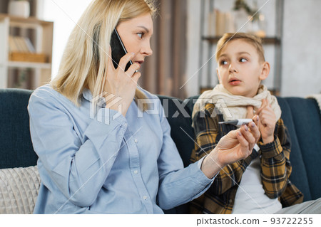 Sad sick teen boy with scarf around neck sitting on sofa at home 93722255