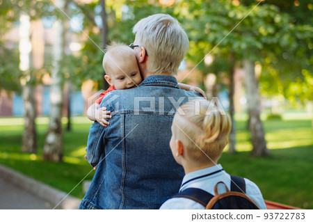 caucasian blond haired woman carry baby daughter. Schoolboy son looking at little sister 93722783