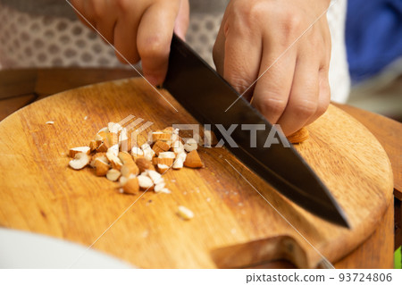 Close up of housewife cutting almond on cutting board for breakfast 93724806