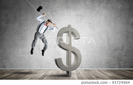 Determined banker man in empty concrete room breaking dollar figure 93724984