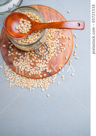 Flat lay. Glass jar with Siberian cedar nuts standing on a wooden stand.  93725338