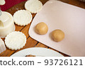 Female hands making dough for mooncake, homemade cantonese moon cake pastry on baking tray before baking for traditional festival. Travel, holiday, food concept 93726121